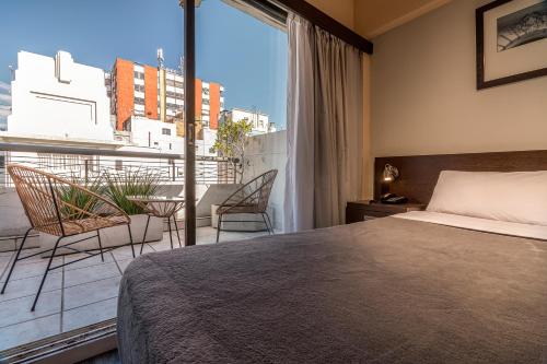 a bedroom with a bed and a balcony with a table at Up Viamonte Hotel in Buenos Aires