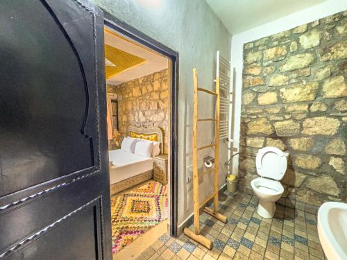 a bathroom with a toilet and a stone wall at Tonaroz House in Imlil