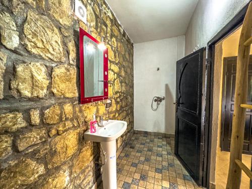 a stone bathroom with a sink and a stone wall at Tonaroz House in Imlil