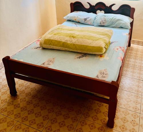a bed with a wooden frame with a yellow blanket on it at Enchanting Oasis in Embu