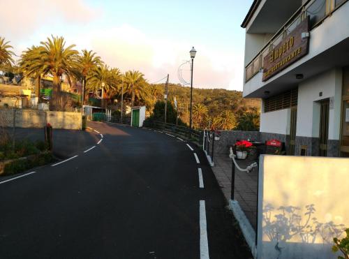 an empty street with palm trees and a building at Casas Rurales Amparo Las Hayas in Valle Gran Rey