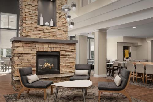 a lobby with a fireplace and chairs and a table at Residence Inn by Marriott Greensboro Airport in Greensboro