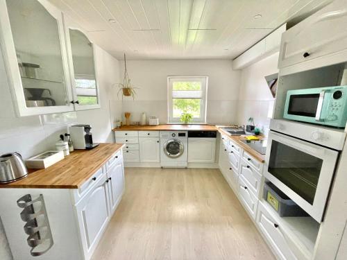 a kitchen with white cabinets and a washer and dryer at Schöne Ferienwohnung mitten im Pfälzerwaldgebiet in Leimen