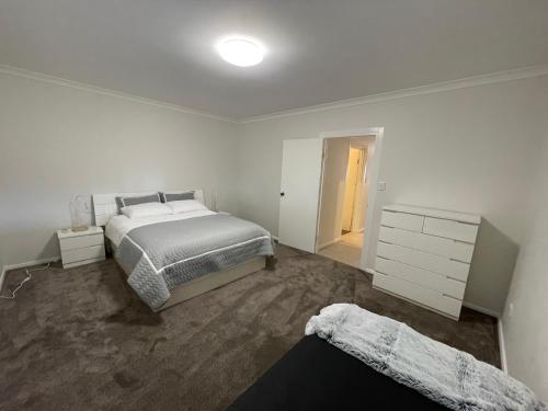 a white bedroom with a bed and a dresser at Springfield Stay - Don-gara Unit in Port Denison
