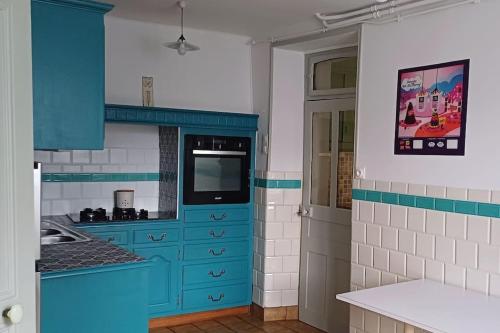 Il comprend une cuisine avec des placards bleus et une télévision. dans l'établissement 3 Aux Dames Vertes, à Cuzion