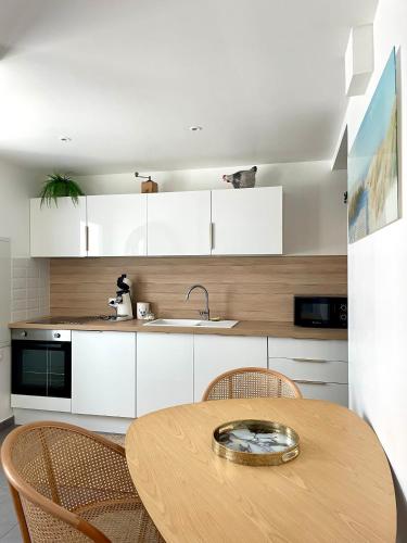 Una cocina con una mesa de madera y gabinetes blancos. en Séjour en Camargue, en Saintes-Maries-de-la-Mer