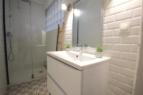 une salle de bain blanche avec un lavabo et une douche dans l'établissement La Cité des Peintres, à Collioure