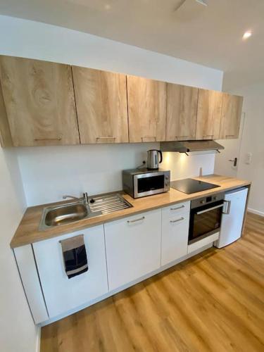 une cuisine avec des armoires blanches, un évier et un micro-ondes dans l'établissement T2 échappée belle Albi, à Albi