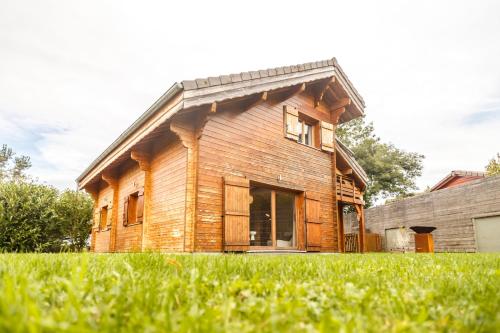 une maison en bois installée au-dessus d'un champ verdoyant et luxuriant dans l'établissement Chalet Ilca, à Thollon-les-Mémises