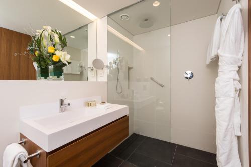 a bathroom with a white sink and a shower at Fraser Suites Geneva - Serviced Apartments in Geneva