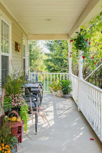 a porch with tables and chairs and flowers at Old Town Country Landing in Niagara on the Lake