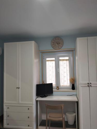 a room with a desk with a computer and a clock at La dépendance in Noci