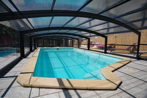 an indoor swimming pool with a glass roof at Maison avec piscine 10 couchages in Pornichet