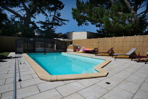 a swimming pool on a patio with two chairs at Maison avec piscine 10 couchages in Pornichet