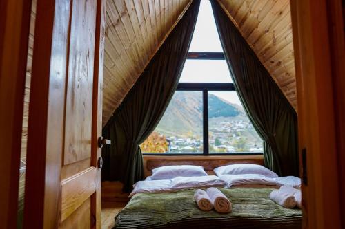 a bed in a room with a large window at Hillside Kazbegi in Stepantsminda
