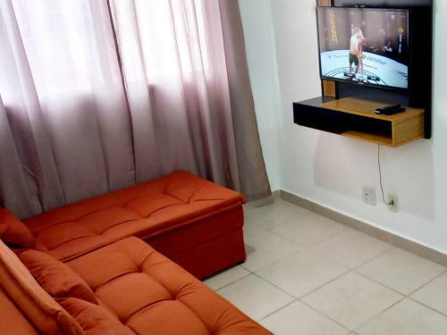a living room with a couch and a flat screen tv at Apto 2Q Sala Cozinha Garagem Wifi Shopping in Taubaté