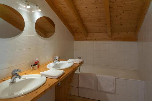 une salle de bain avec deux lavabos et une baignoire dans l'établissement Chalet Ruisseau, aux Gets