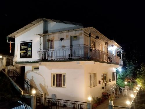 a white house with a balcony at night at Sanchi's Homestay 2BHK in Bhowāli