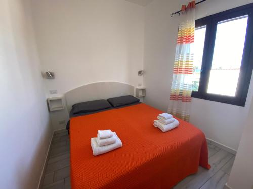 a bedroom with an orange bed with towels on it at Nora's Flats in Triscina