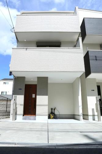 a white house with a door and a driveway at 雅舍11 Osaka house new open一軒家貸切 in Osaka