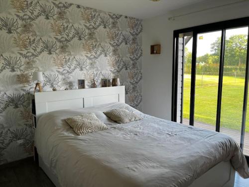 une chambre avec un grand lit avec une grande fenêtre dans l'établissement Maison au calme, à Saint-Jean-des-Champs