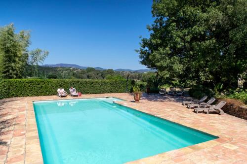 - une piscine dans une cour avec des chaises et un arbre dans l'établissement Les Gites du Merle, à Cogolin