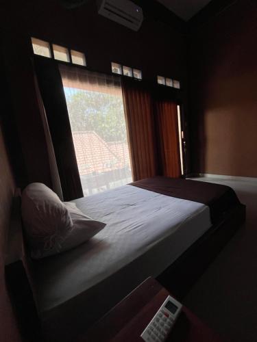 a bedroom with a bed with a window and a remote control at Fullmoon homestay in Kuta Lombok