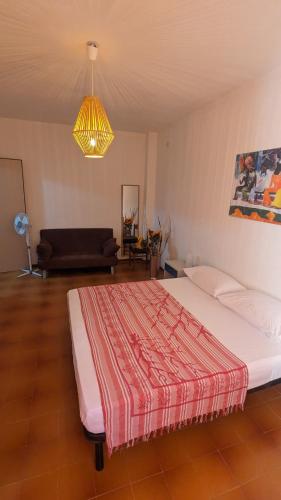 a bedroom with a bed and a couch and a chandelier at Appartamento Nerium - Cala di Seta in Calasetta