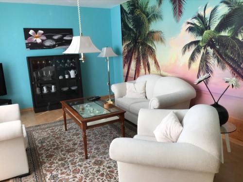 a living room with two white couches and a table at Ferienwohnung Margarethe in Papenburg