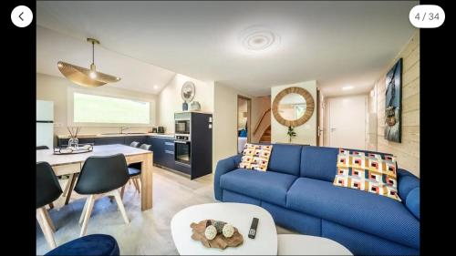 a living room with a blue couch and a kitchen at Ô songes de Saxel in Saxel
