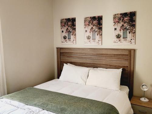 Un dormitorio con una cama con dos cuadros en la pared. en Sable woods, en Pretoria