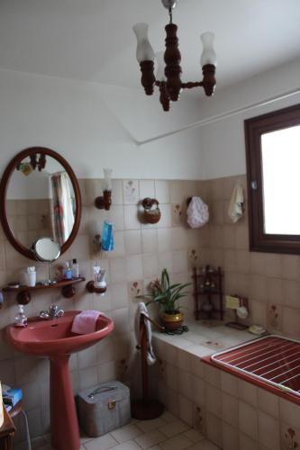 La salle de bains est pourvue d'un lavabo rouge et d'un miroir. dans l'établissement Maison de famille, à La Teste-de-Buch