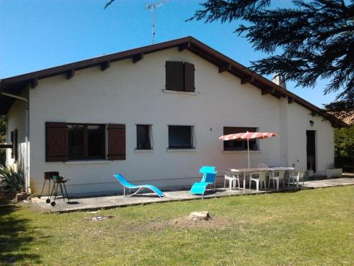 une maison avec deux chaises, une table et un parasol dans l'établissement Maison de famille, à La Teste-de-Buch