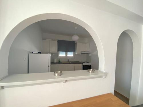 a white kitchen with an archway and a white refrigerator at Villa Libra-Skiathos in Skiathos Town
