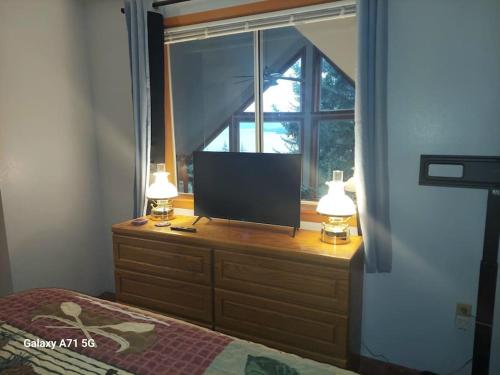 a tv on a dresser in a bedroom with a window at Hunter's Haven in Haines