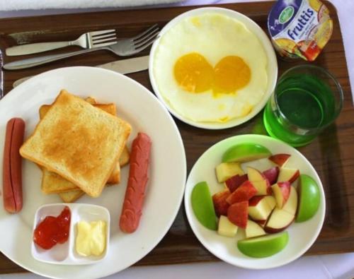 ein Tablett mit zwei Tellern Frühstücksspeise mit Eiern und Obst in der Unterkunft Crystal sea inn in Bileffahi