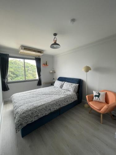 a bedroom with a bed and a chair and a window at Hot Deal ! Sea View Condo Cozy & Charming Si Racha in Si Racha