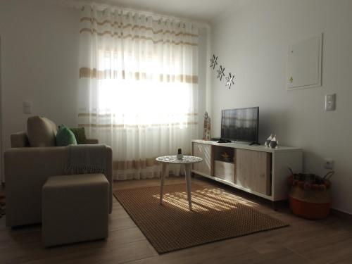 a living room with a couch and a table and a television at Aldeia na Praia - Vale Furado in Pataias