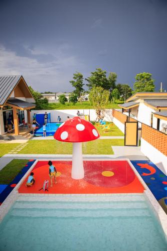a toy garden with a red umbrella in a pool at ongsa house chiang mai pool villa in Ban Mae Hom