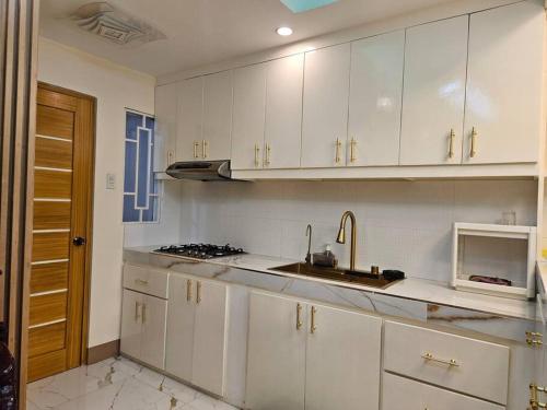a kitchen with white cabinets and a sink and a microwave at Family Friendly House in Malolos
