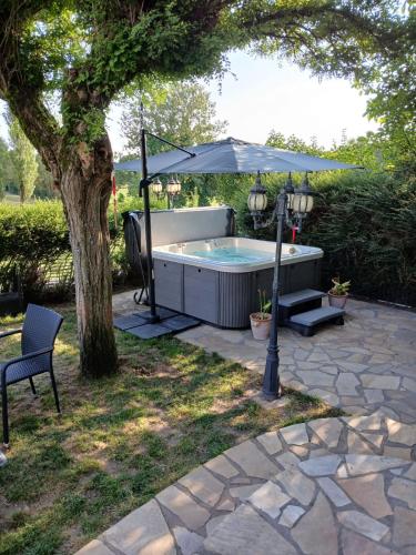 a hot tub with an umbrella next to a tree at L'Aurigast in Auriac-Lagast