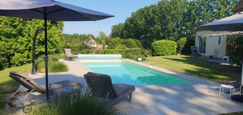 une piscine avec deux chaises et un parasol dans l'établissement La Paudila, à Saint-Martin-de-Gurçon