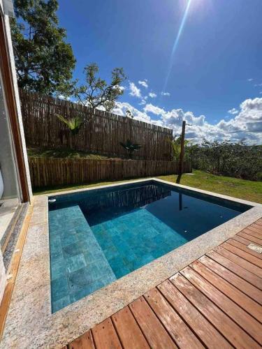 a swimming pool on a deck with a wooden fence at OKA VIVAH - Chalé Oka da Montanha in Jaboticatubas