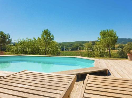 une piscine avec une terrasse en bois et une visière de piscine dans l'établissement Suite ou chambre privée à la Forge des Cyprès, à Loupia