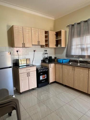 a kitchen with wooden cabinets and a stove top oven at Munyonyo Apartment in Kampala
