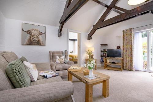 a living room with a couch and a cow on the wall at Jasmine Cottage in Paignton