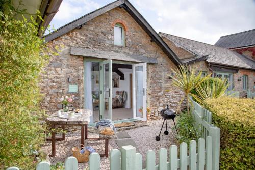 a stone cottage with a white fence in front of it at Jasmine Cottage in Paignton