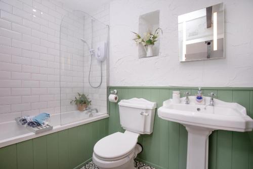 ein grün-weißes Badezimmer mit Toilette und Waschbecken in der Unterkunft Daisy Cottage in Paignton