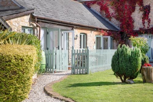 a house with a white fence and a yard at Daisy Cottage in Paignton