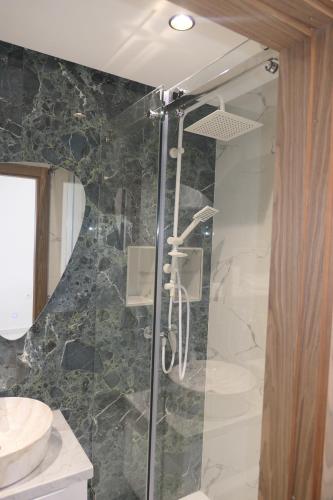 a bathroom with a glass shower with a sink at Les portes de Temara in Temara